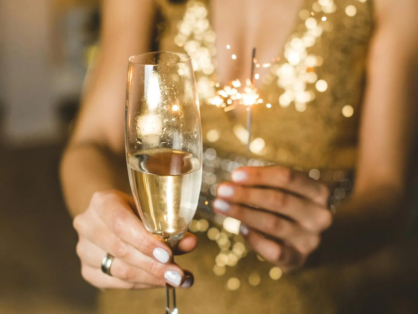 Woman in a gold sequin dress holding a glass of champagne