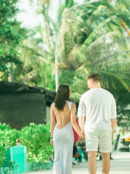 A couple walking together hand in hand along a palm-lined path