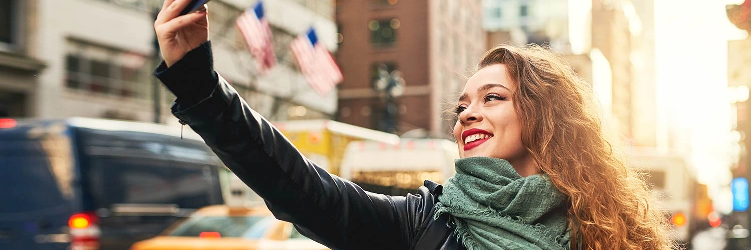 Single Female New Yorker taking a selfie in the busy New York city streets for her dating profile app