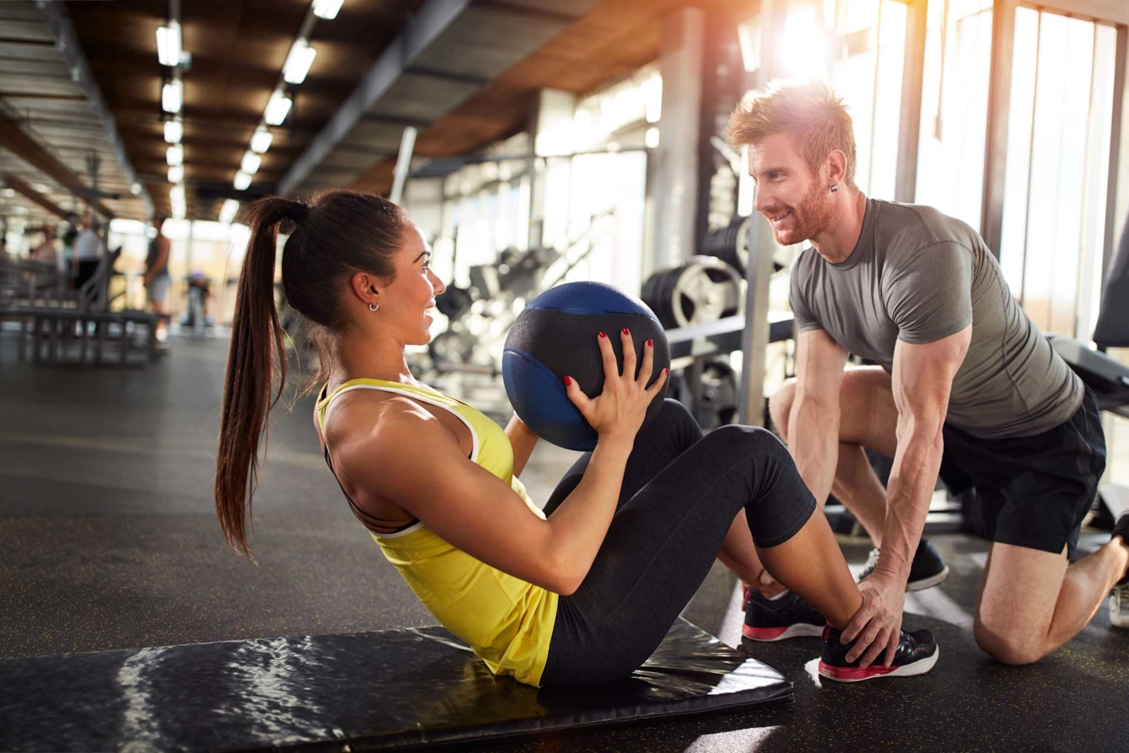 A woman and a man laughing during a medicine ball workout, active singles in North Carolina