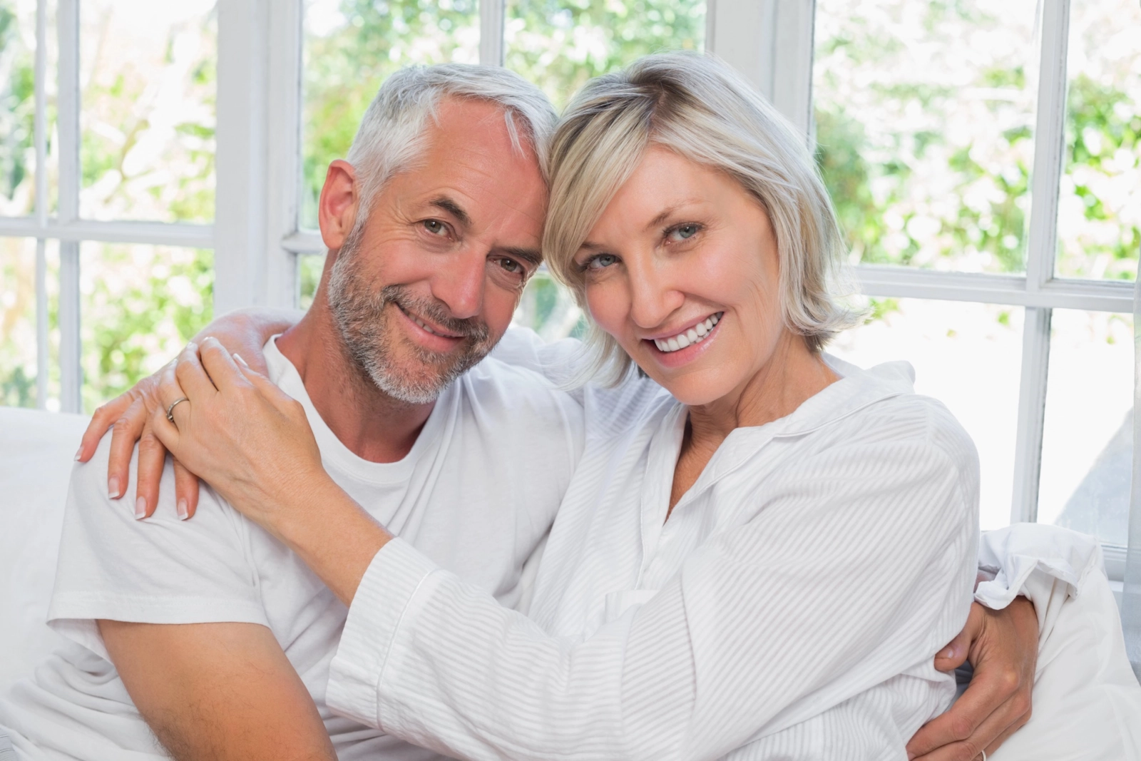 A happy mature couple embracing and smiling together at home
