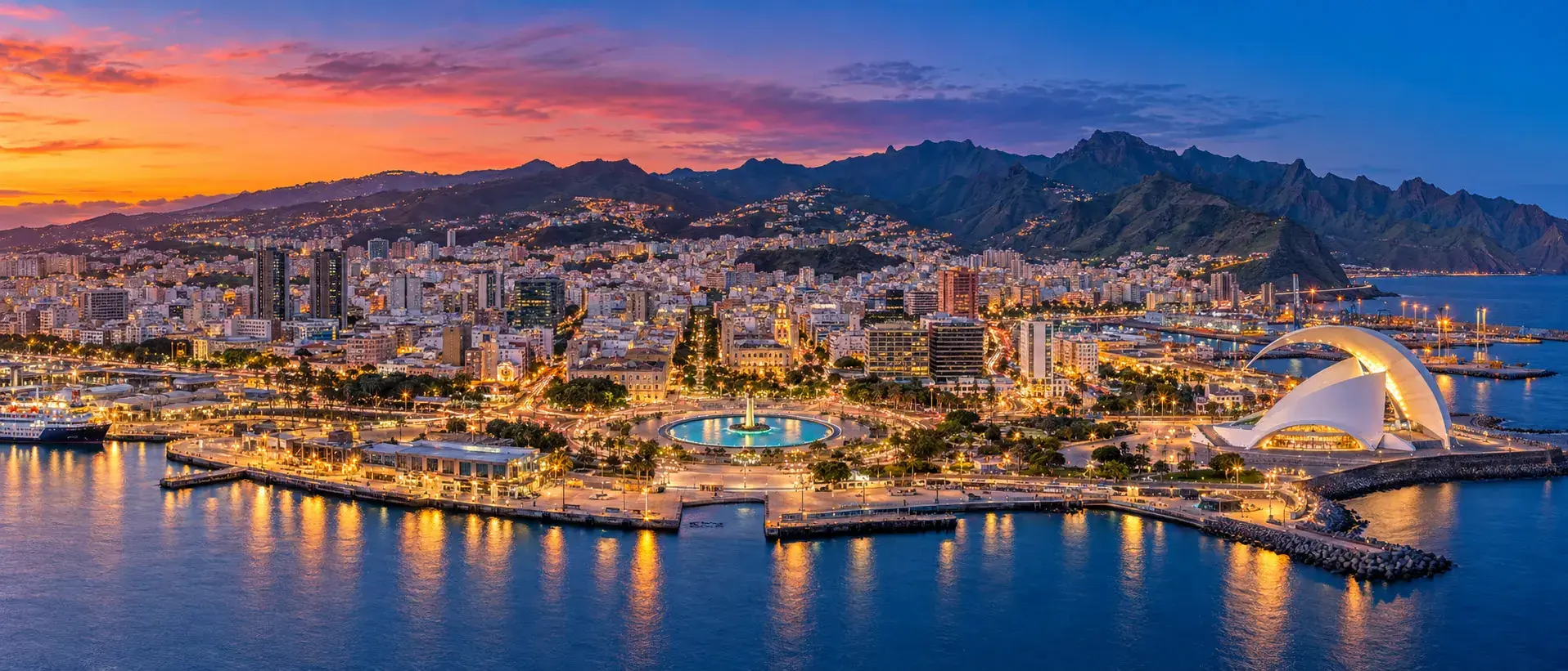 Santa Cruz de Tenerife al anochecer con la Plaza de España, el Auditorio de Tenerife junto al puerto y el macizo de Anaga al fondo