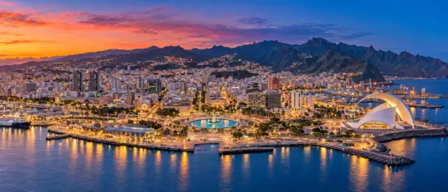 Santa Cruz de Tenerife al anochecer con la Plaza de España, el Auditorio de Tenerife junto al puerto y el macizo de Anaga al fondo