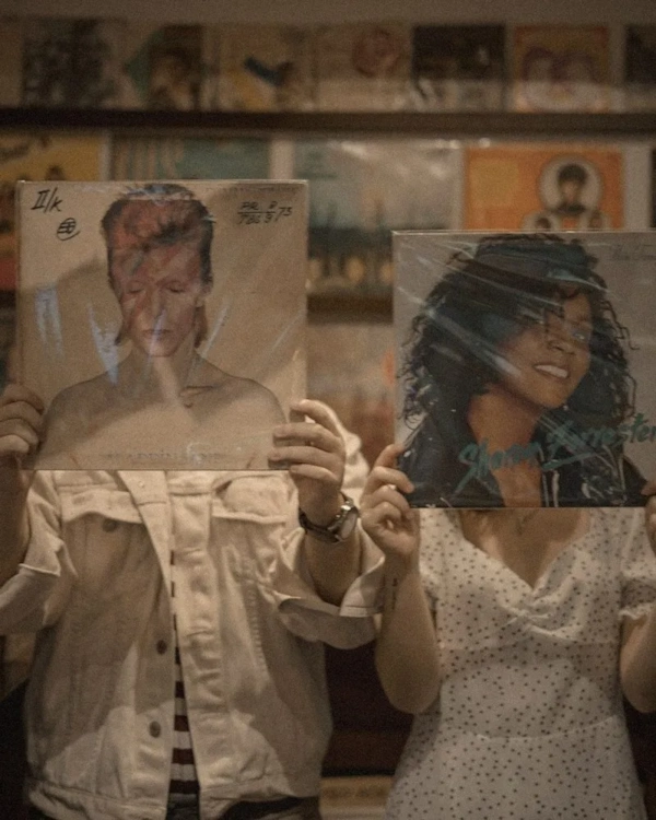 Couple holding up vinyl record sleeves in a record shop