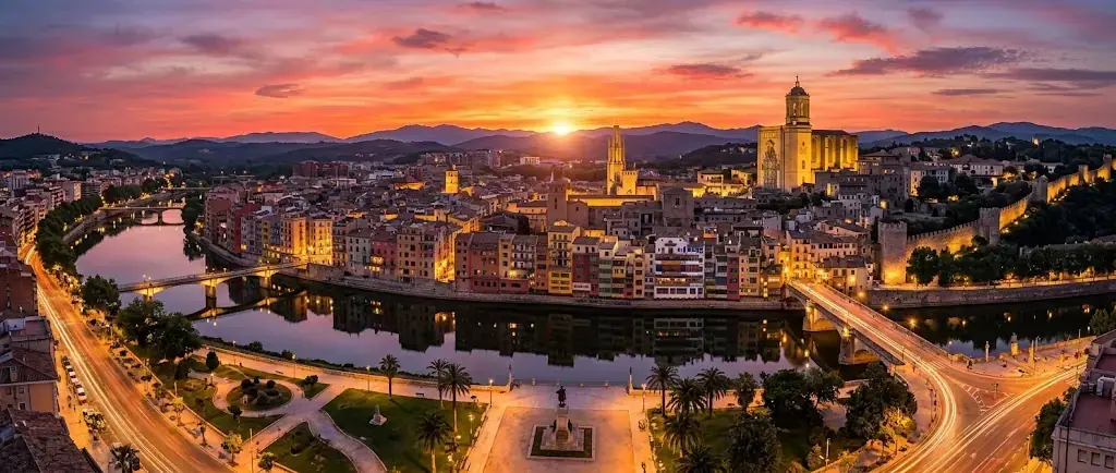 Vista aérea de Girona al atardecer, con la catedral y las casas del río Onyar iluminadas