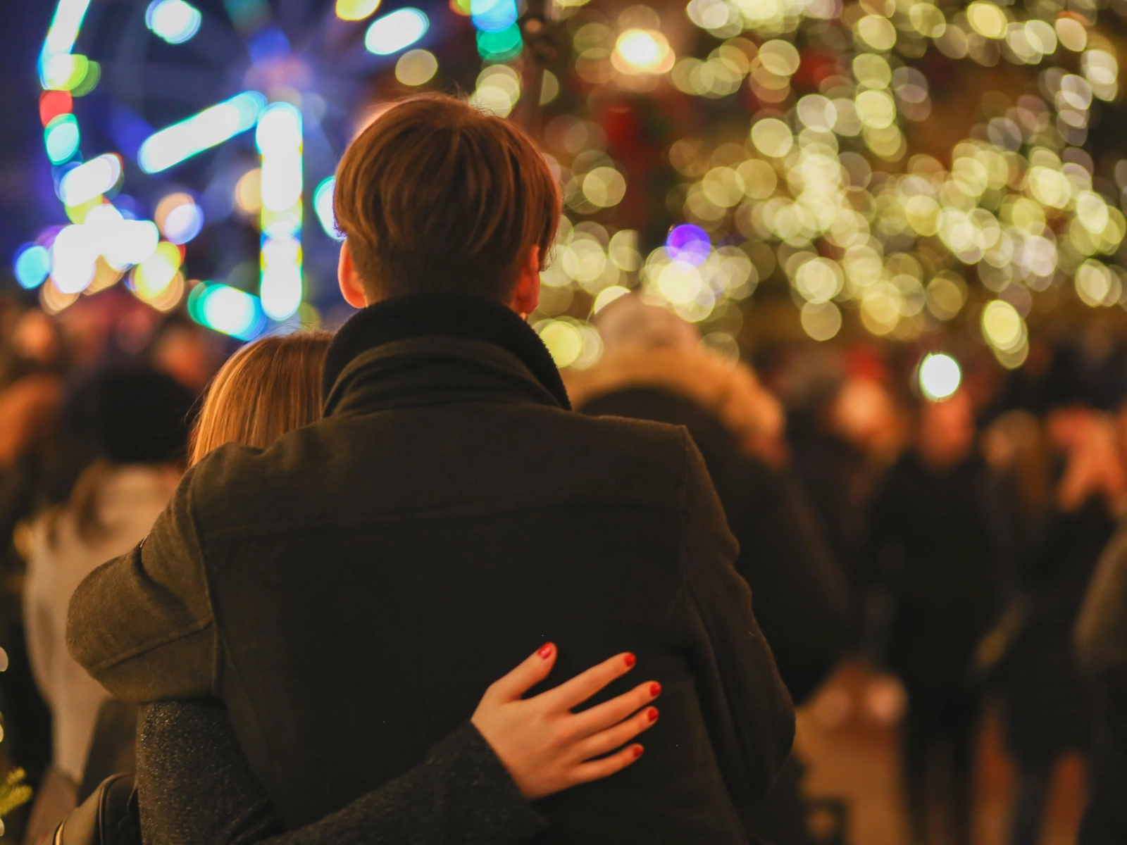 Couple hugging in front of glowing evening lights