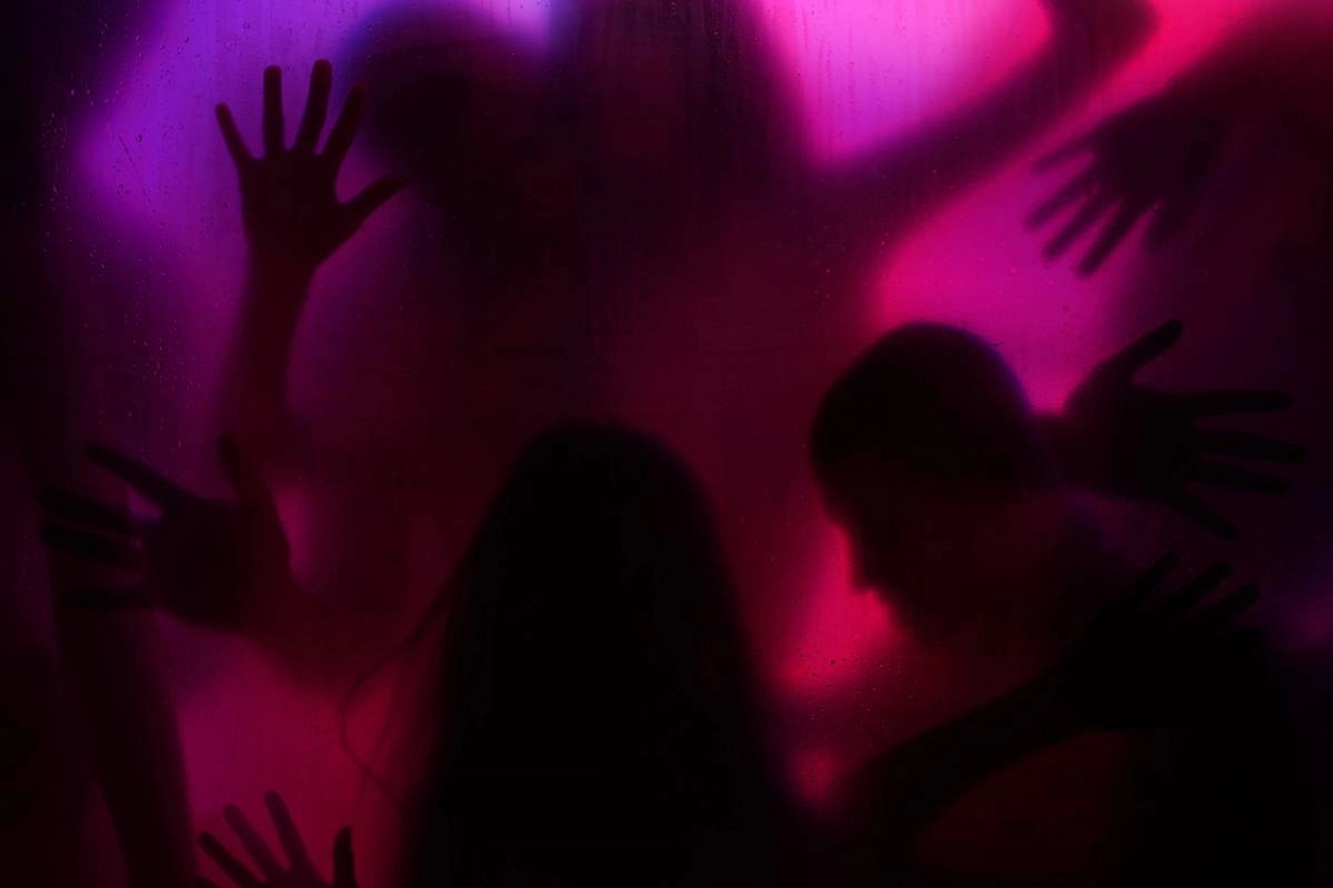 Silhouettes of people behind a frosted screen, lit in red and purple