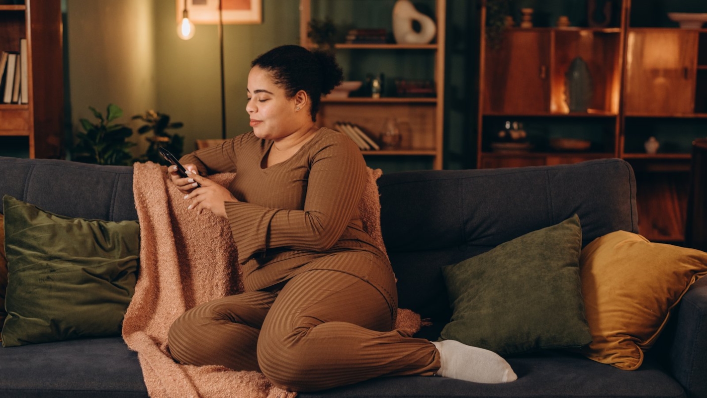 A woman relaxing on the sofa at home, checking her phone