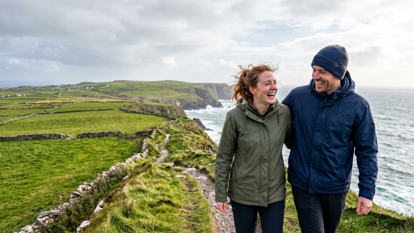A couple in rain jackets laughs as they walk along a green clifftop path above the Atlantic, stone walls running across the fields (AI-generated image)