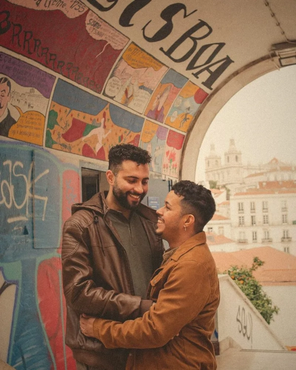 Two men embracing in front of a colourful mural