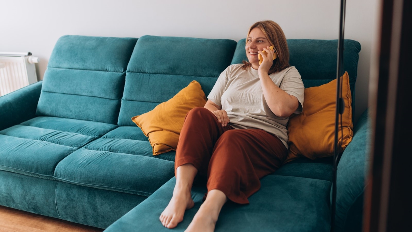 A woman laughing during a phone call at home