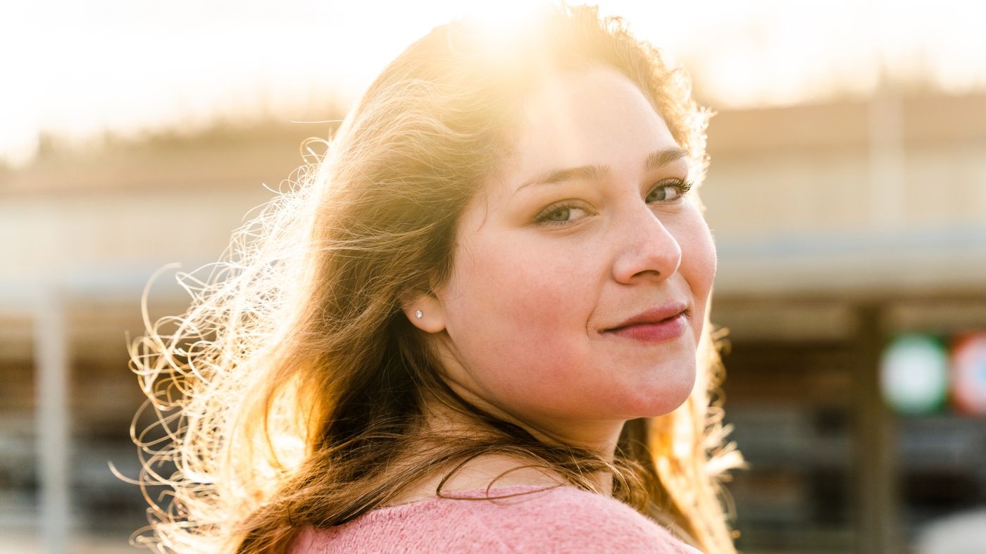 A Curvalicious member smiling in golden-hour light, an example of a warm, confident dating profile photo
