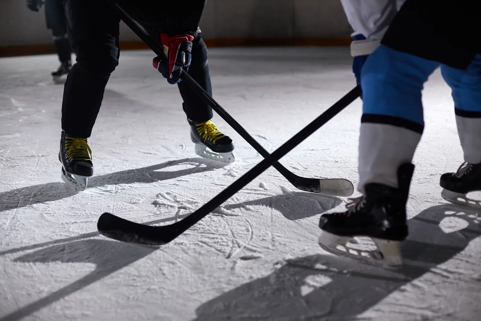 Two hockey sticks crossing on the ice as players battle for the puck