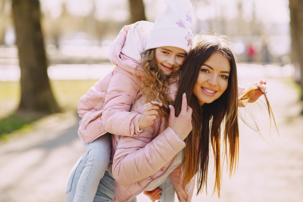 Illustrative photo of a mother giving a child a piggyback ride in a park