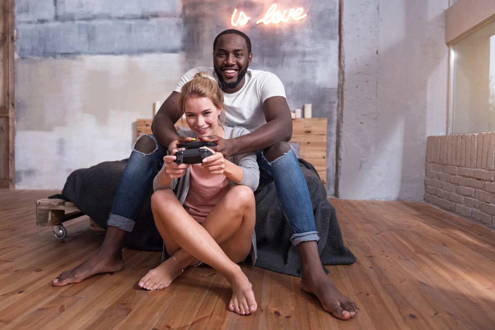 A couple on a wooden floor sharing a games controller