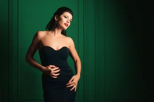 A woman in a black dress standing against a deep green wall