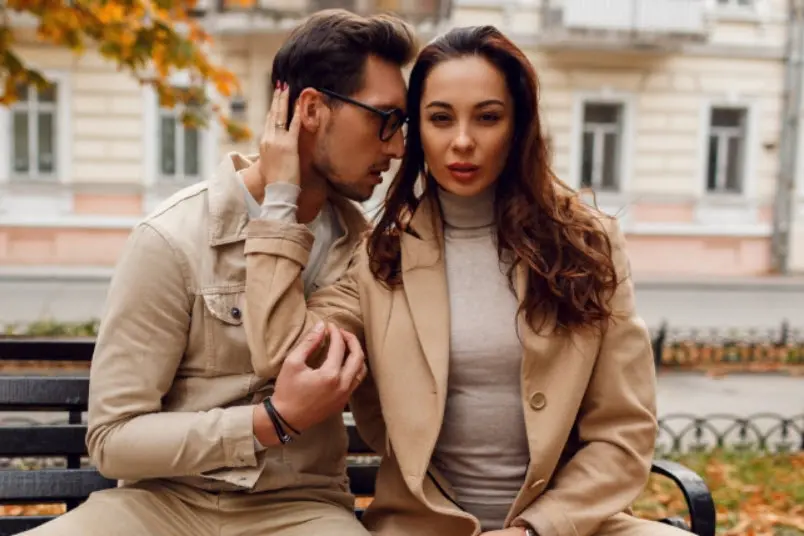 Maduras que buscan jóvenes discretos: pareja con abrigos beige sentada en un banco de un parque en otoño