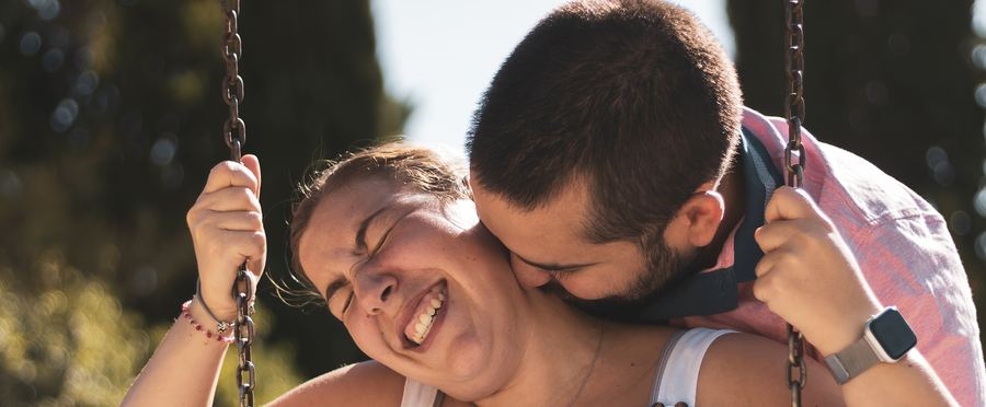 A laughing couple sharing a moment on a swing