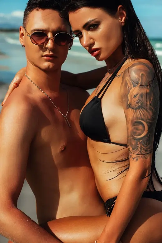 A couple standing close together outdoors on a summer day