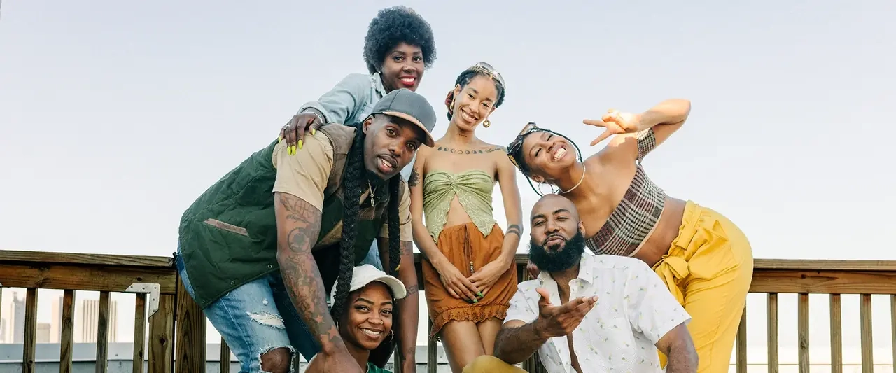 A group of friends laughing and posing together on a wooden deck