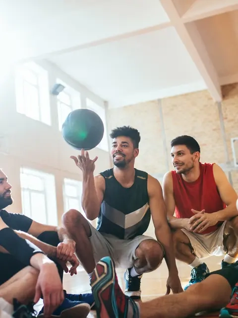 Friends in sports gear laughing together on an indoor basketball court
