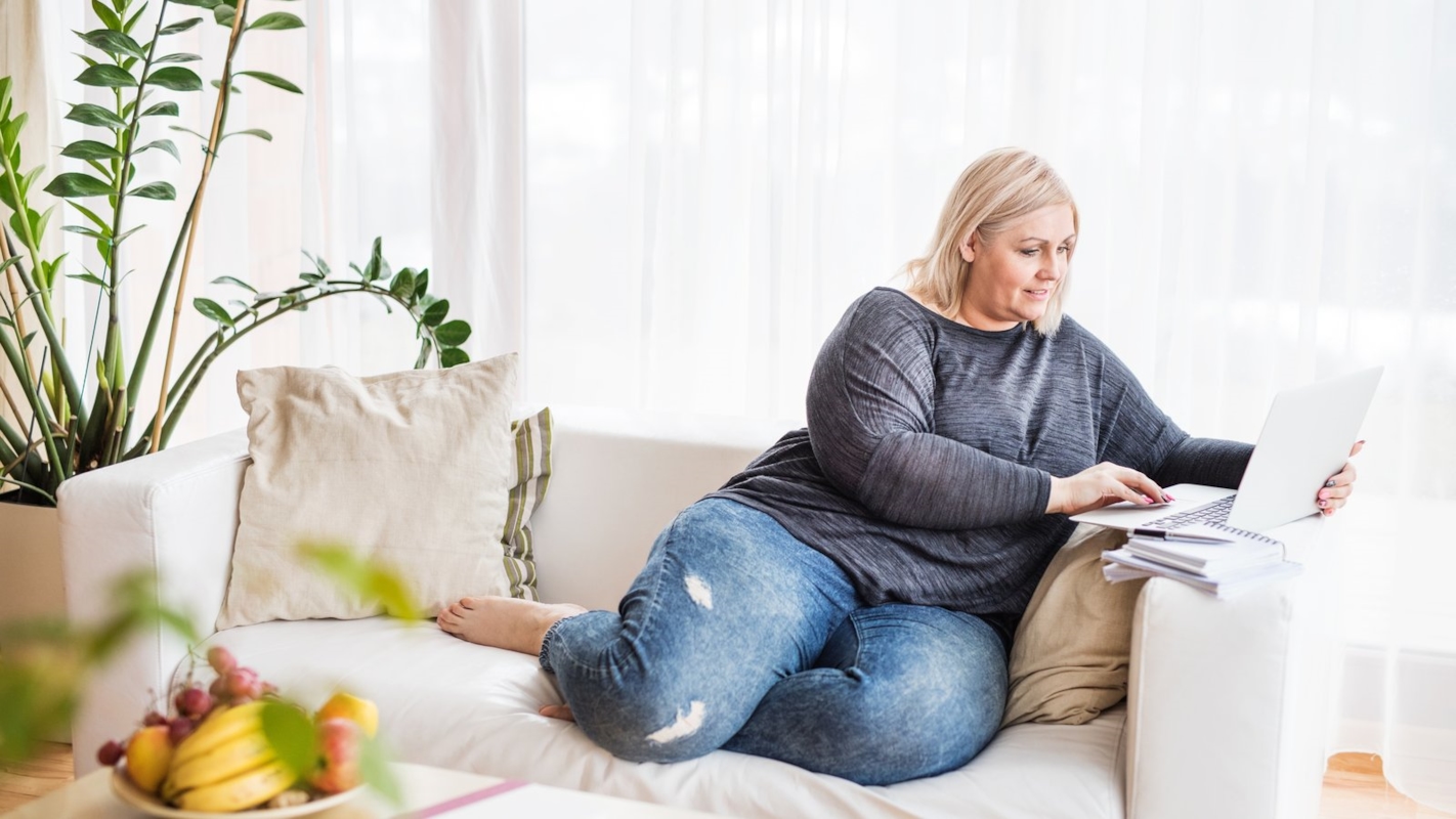 A woman relaxing on her sofa with a laptop
