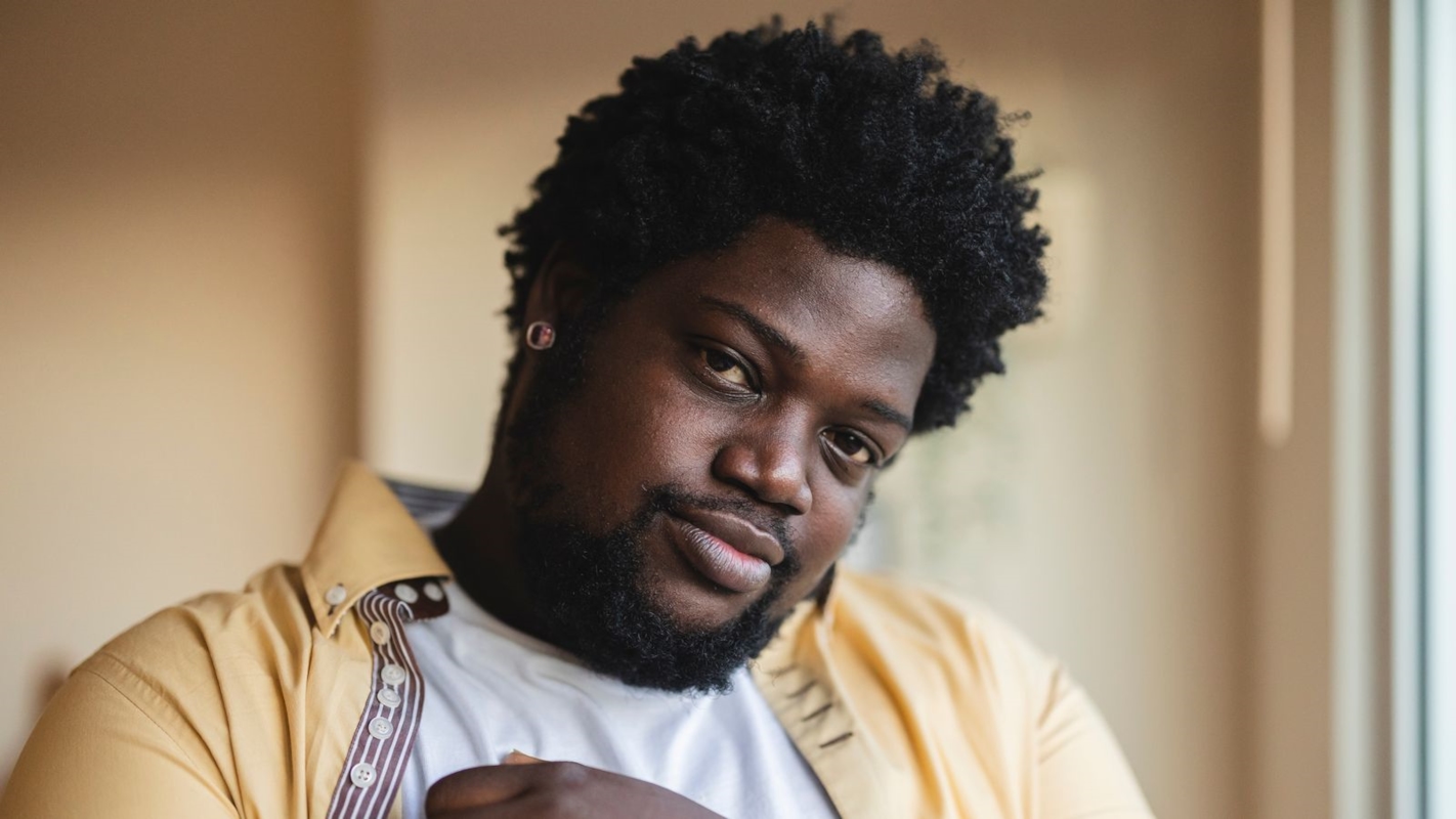 A man with a warm, thoughtful expression, backlit by natural light