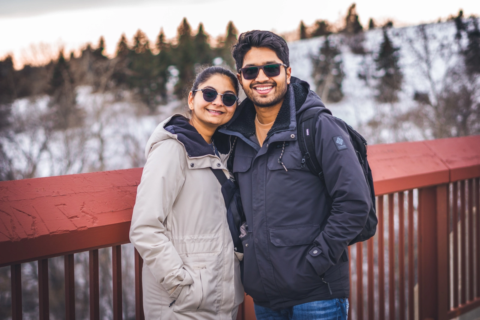Smiling couple in winter jackets at a snowy lookout