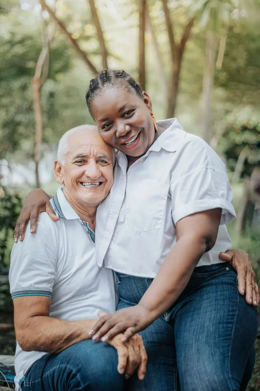 A laughing couple hugging on a bench in a sunny park