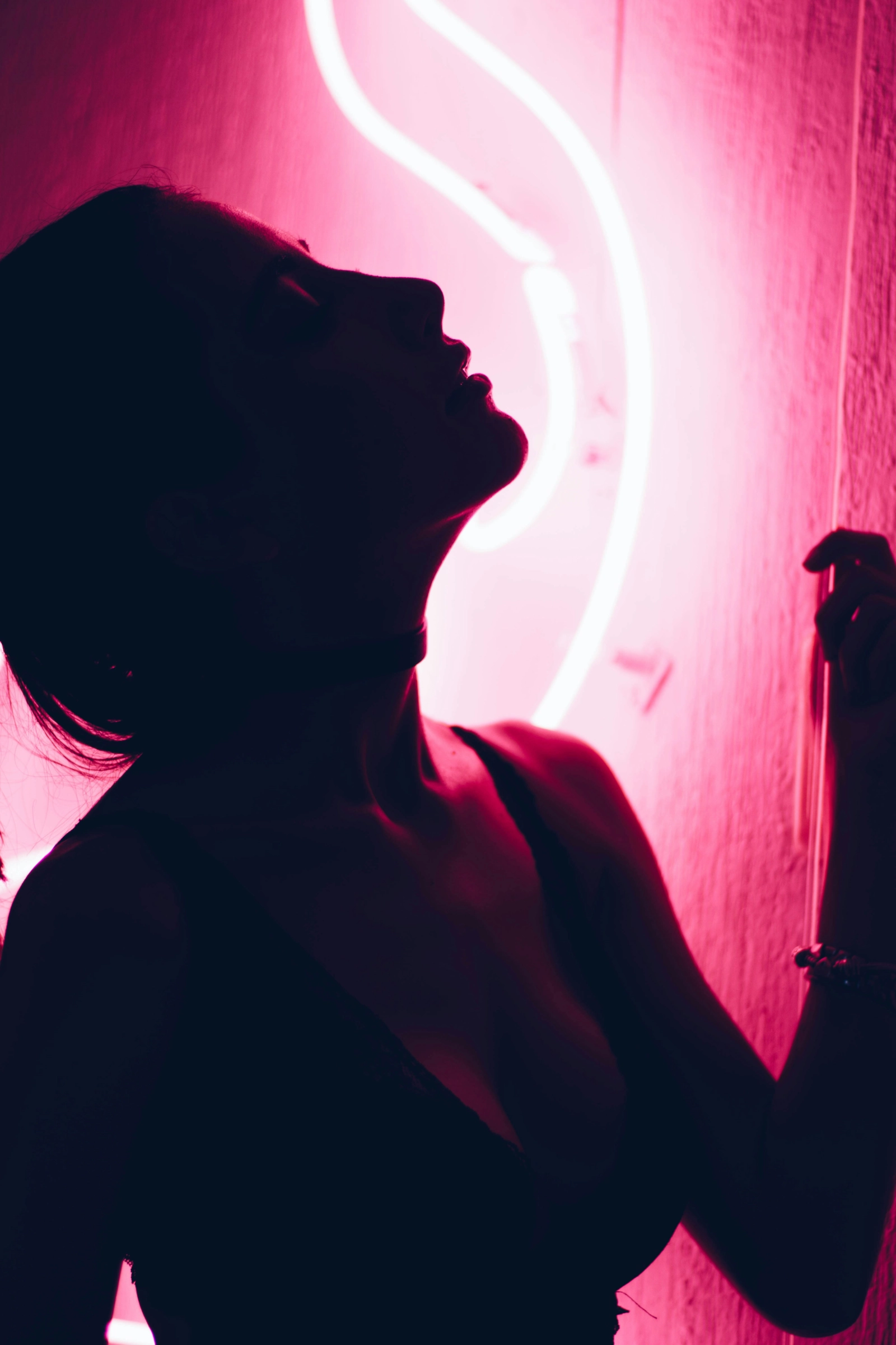 Silueta de una persona a contraluz ante una luz de neón rosa