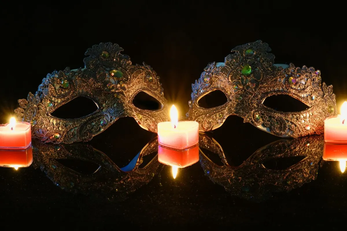 Two masquerade masks beside lit candles