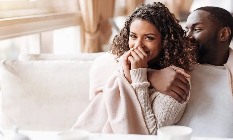 A couple laughing together on a sofa at home