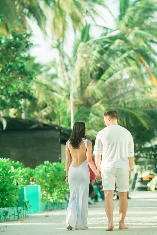 A couple walking away together along a path lined with palm trees