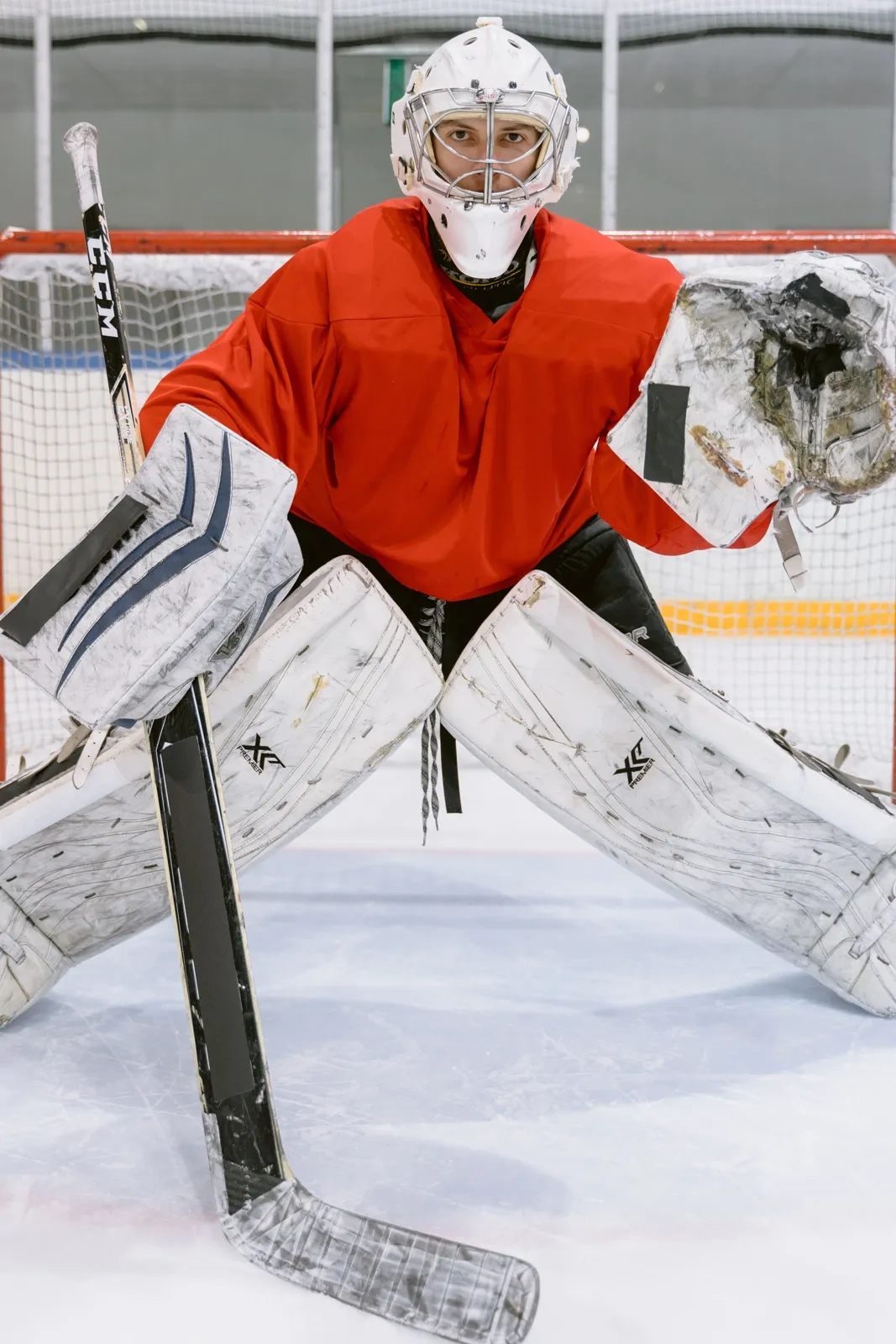 A goalie in an orange jersey crouched in the crease
