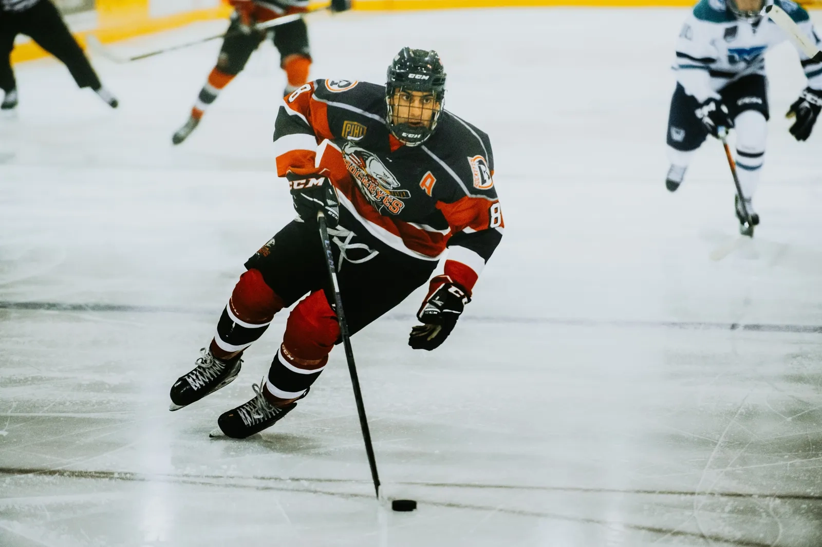 Skater driving forward with the puck while opponents trail behind