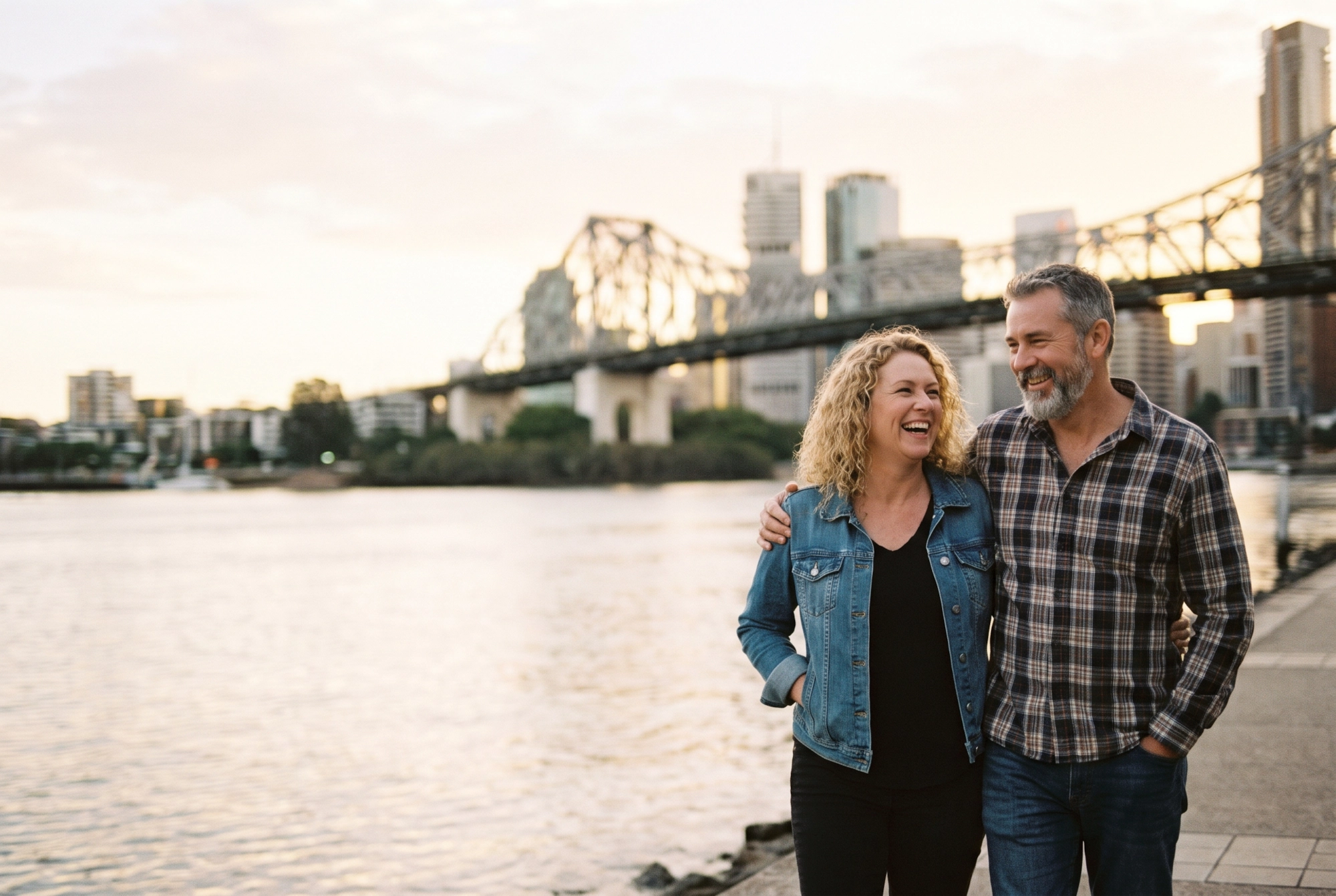 A happy couple laughing together at South Bank with the Story Bridge and the Brisbane skyline behind them