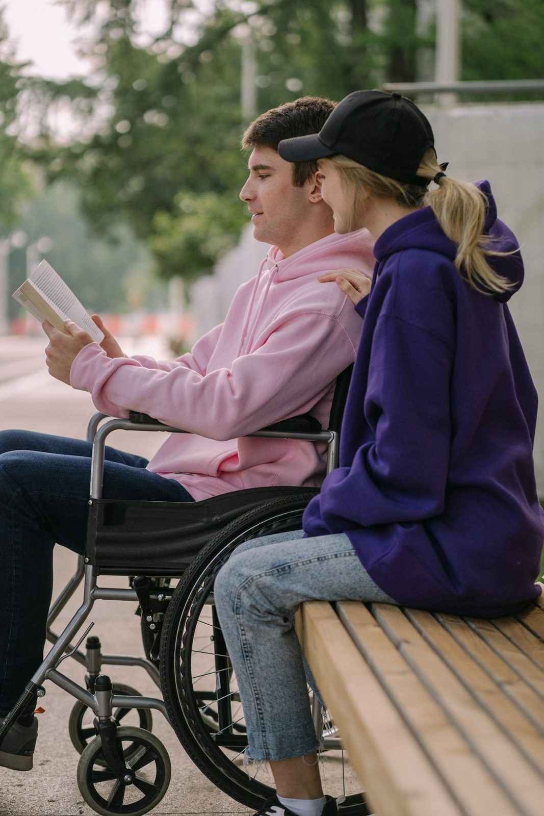 A wheelchair user chatting with a friend on a park bench