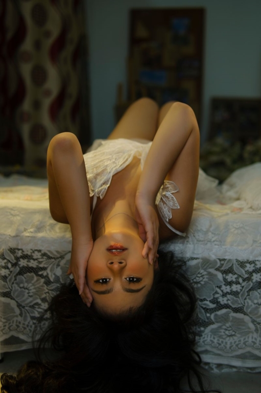 Woman in white lace lying back on a bed