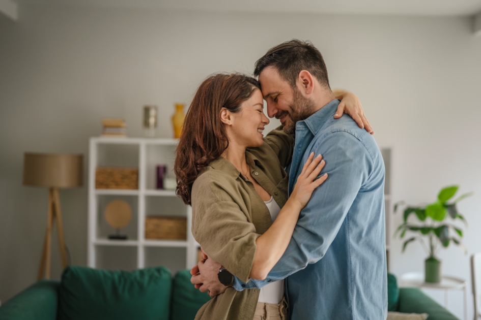 Couple in an intimate embrace at home, smiling at each other