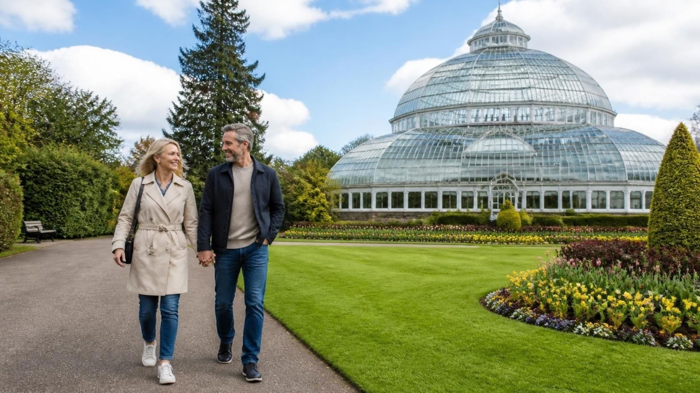 A couple walking hand in hand past a Victorian glasshouse in a botanic garden