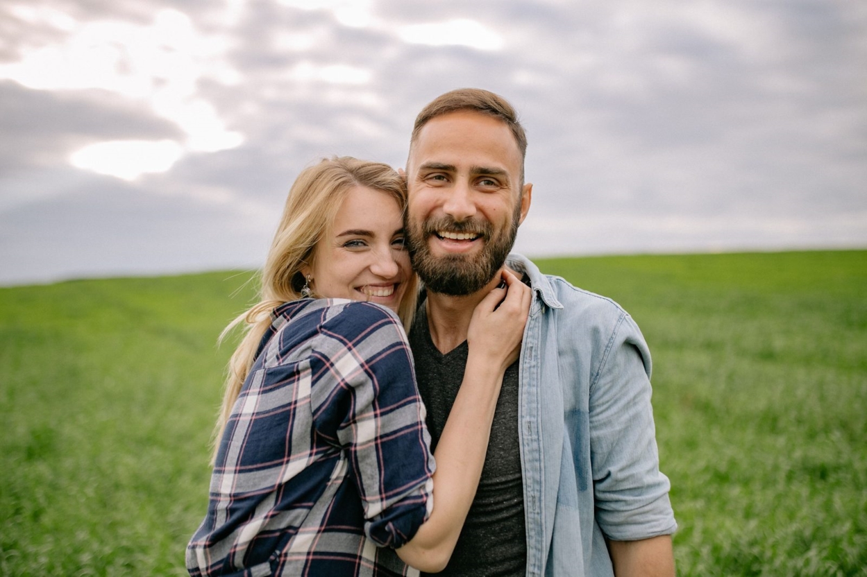 Happy young couple smiling together in a green field
