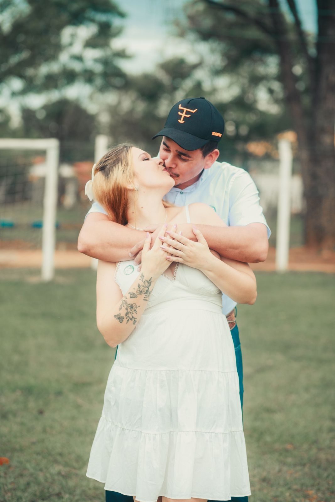 A couple sharing a kiss on a grass football pitch