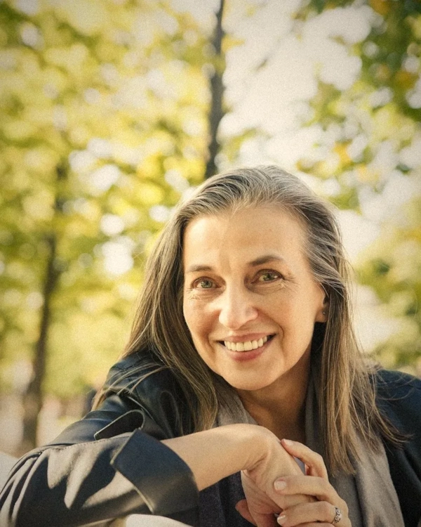 Smiling woman with a grey streak sitting in a park