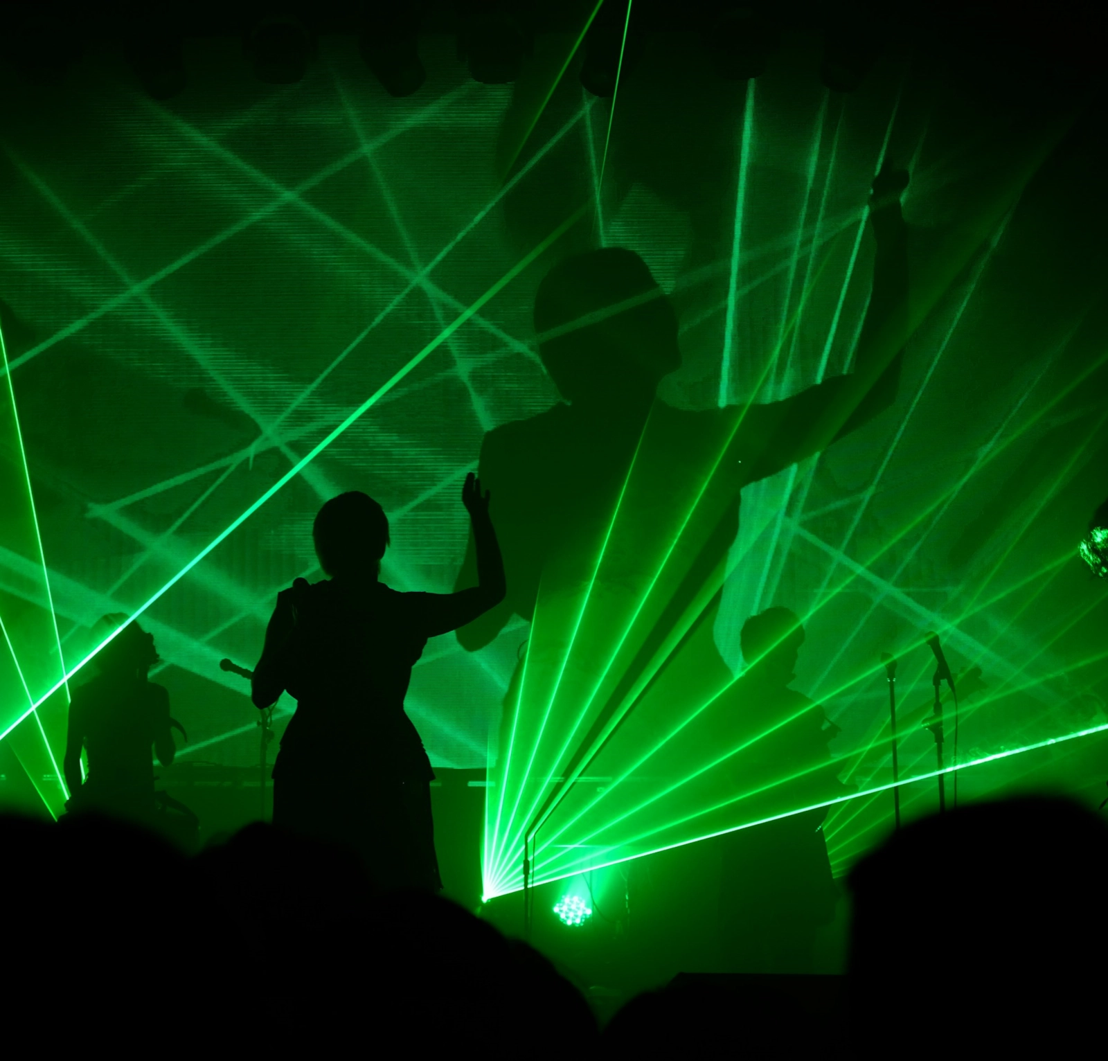 Silhouettes on stage under green laser lights