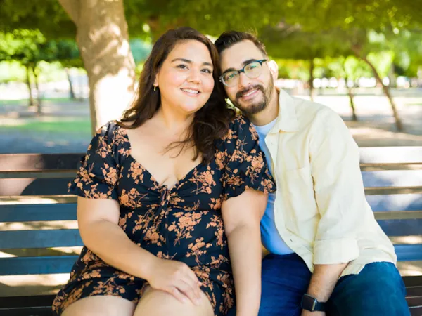 A smiling couple sitting close together on a park bench
