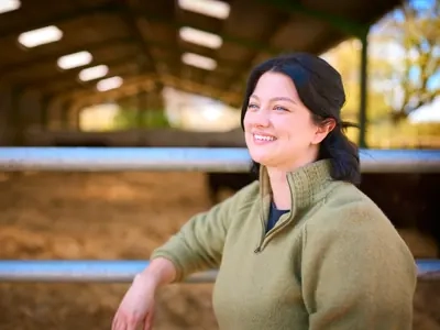 A woman smiling in a barn at the end of the day