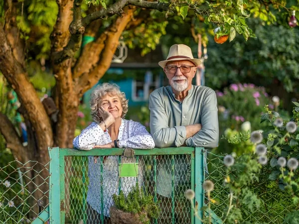 A couple standing at the gate of a vegetable garden