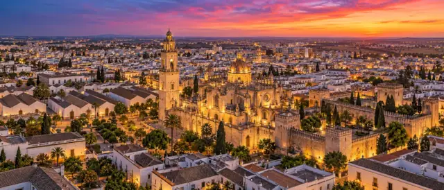 Jerez de la Frontera al atardecer con la catedral y el Alcázar iluminados entre casas encaladas y naves de bodega