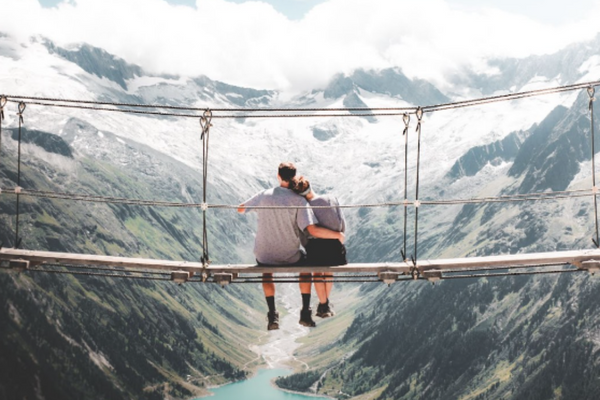 A couple sitting together on a bridge outdoors