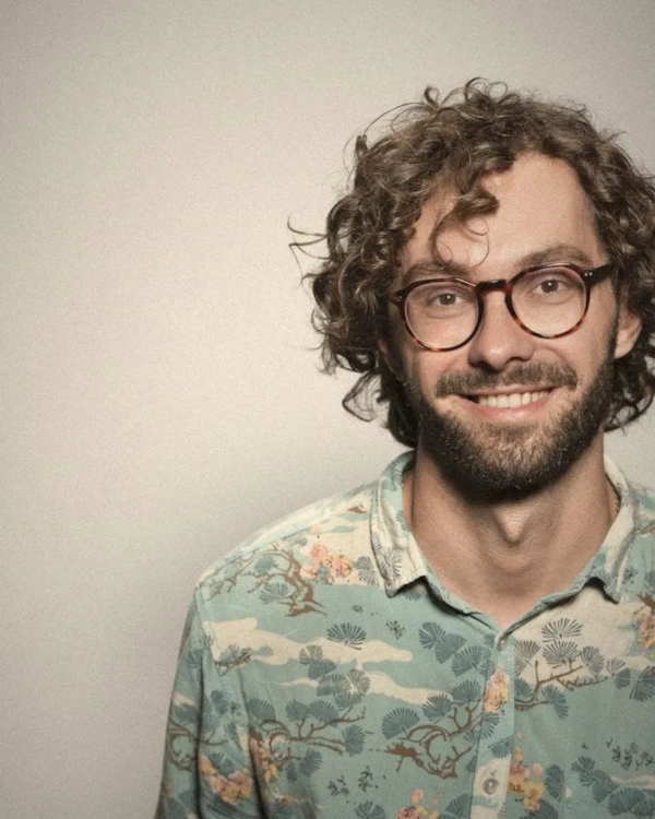 Smiling man with curly hair, glasses and a beard